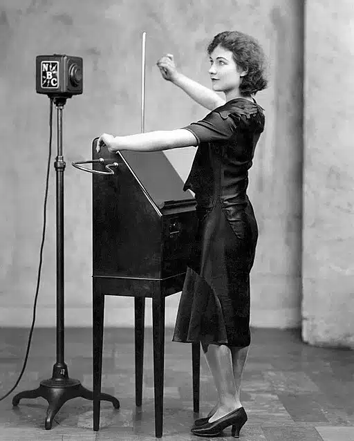 An old black and white photo of a woman playing the theremin, an uncommon instrument.